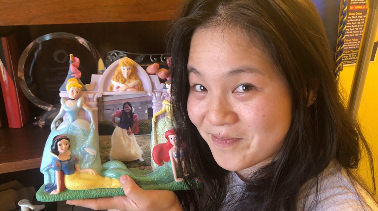 Kelly Marie Tran holding a picture of her younger self as Snow White.