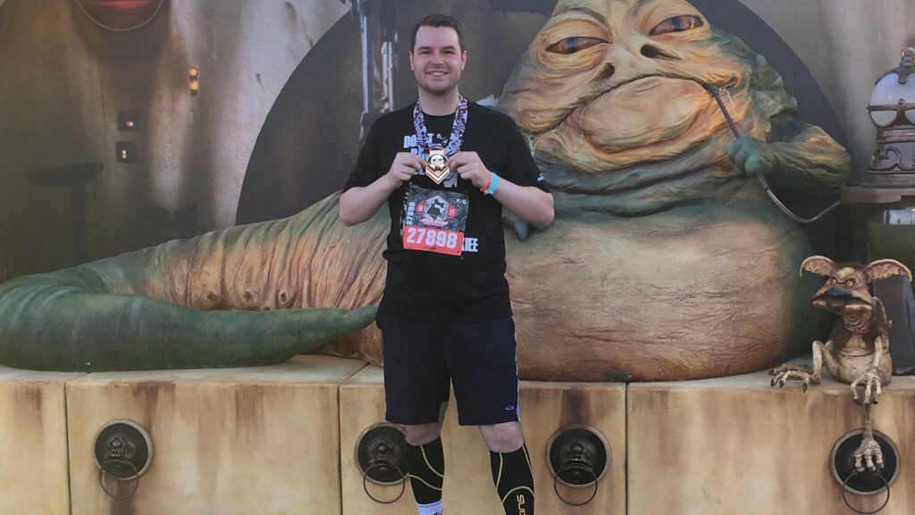Runner Devin Reed poses with a medal in front of a Jabba the Hutt statue.