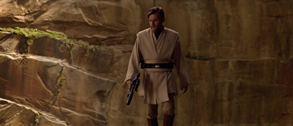 Obi-Wan Kenobi walks through a cavernous area with his blaster in Revenge of the Sith.