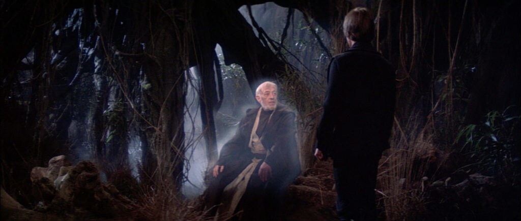 The ghost of Obi-Wan Kenobi sits on a log as he talks to Luke Skywalker in Return of the Jedi.