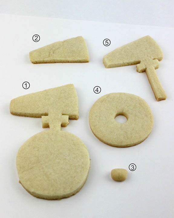 Pieces of cookie dough cut out from a D-O uni-roller template and labeled 1 through 5.