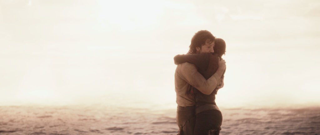 Jyn Erso and Cassian Andor embrace on the beach of Scarif before it's destroyed.