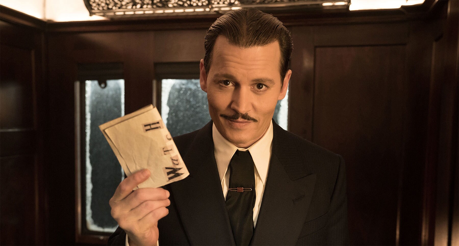 Johnny Depp (as Edward Ratchett) holding a piece of paper in his hand in "Murder on the Orient Express"