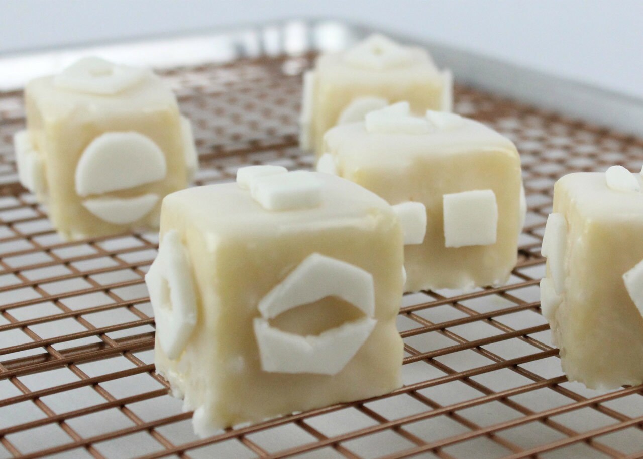 Cake cubes with fondant symbols cool on a wire rack.