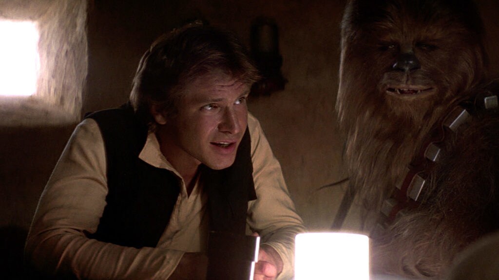 Han and Chewie sit at a table in the Mos Eisley Cantina in A New Hope.