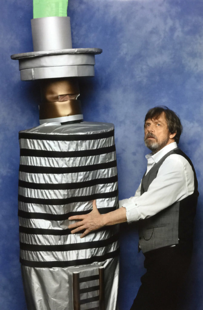 Mark Hamill poses with a fan in a lightsaber costume.