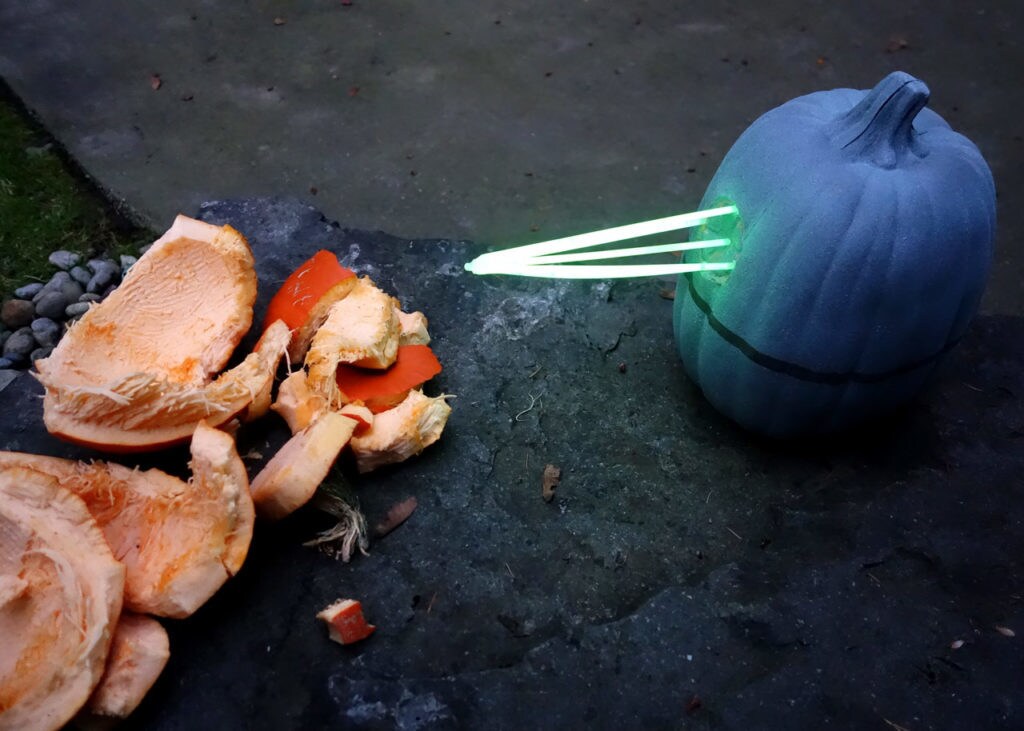 A pumpkin made to look like the Death Star firing its main weapon at a pile of pumpkin pieces.