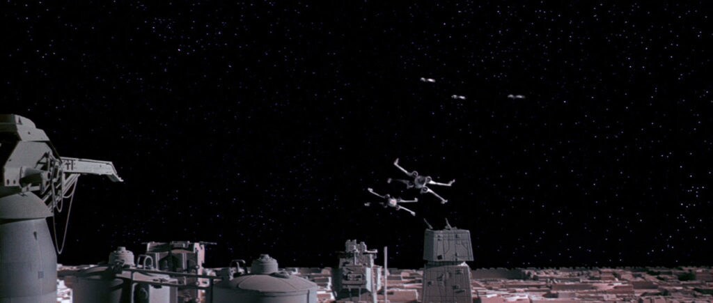Two X-wings fly over the surface of the Death Star.