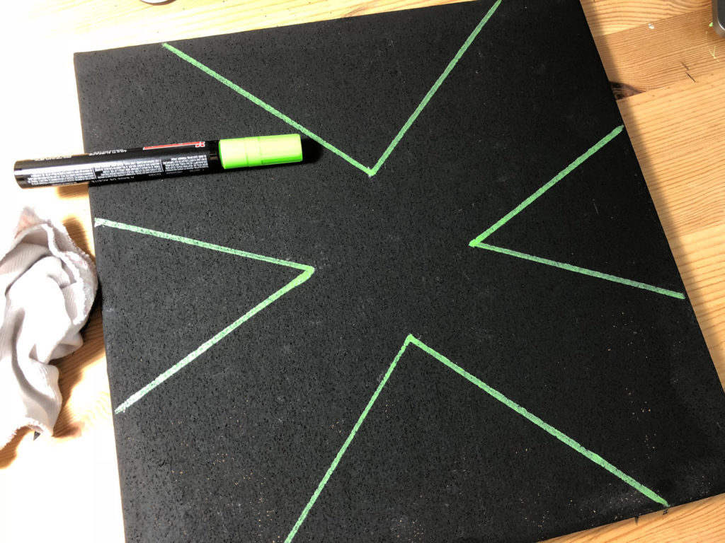 A black cork board with green lines drawn on it.
