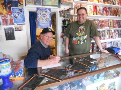 John Morton, who played Dak Ralter in The Empire Strikes Back, signs autographs at the Automattic Comics & Toys shop while the owner, Matt Booker, stands next to him.