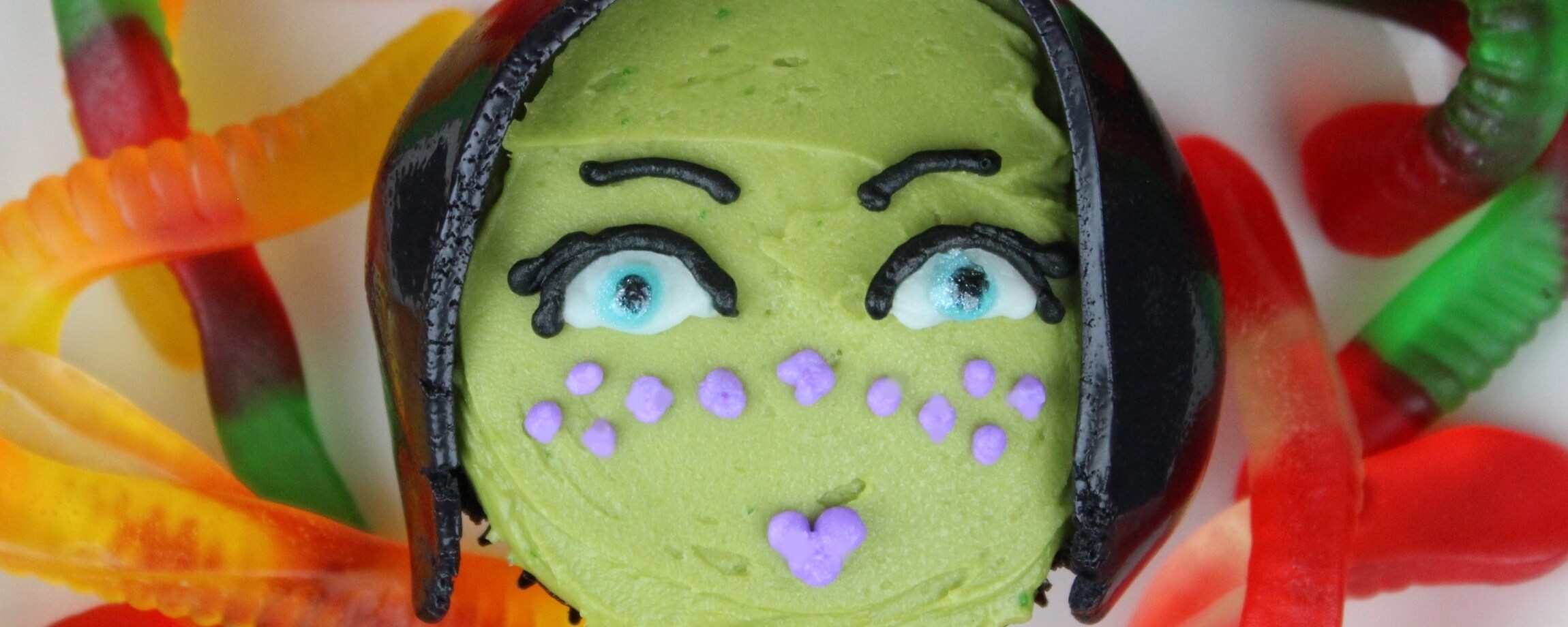 A cupcake decorated to look like Jedi knight Barriss Offee on top of gummy worms.