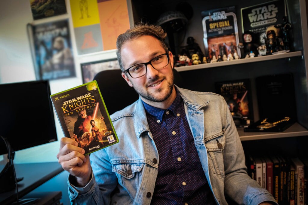 A member of the Lucasfilm Games Team holds up a copy of Knights of the Old Republic.