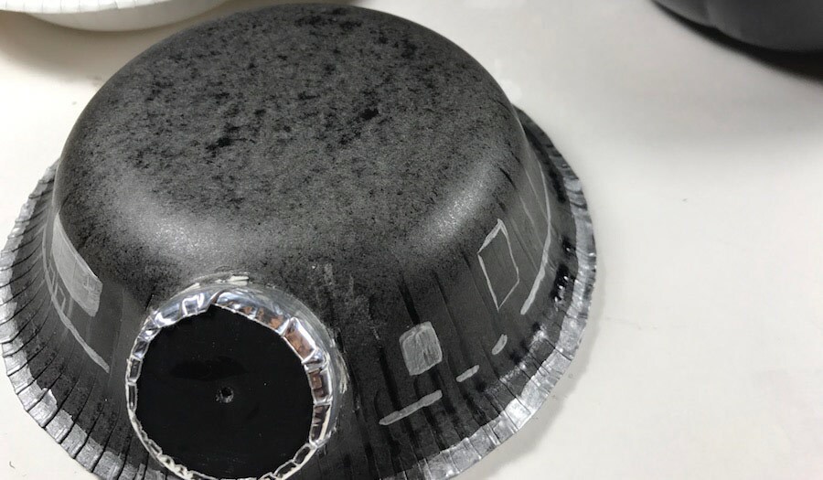 A black and silver upside down paper bowl with a bottle cap makes up the top of the BB-9E-o-lantern.