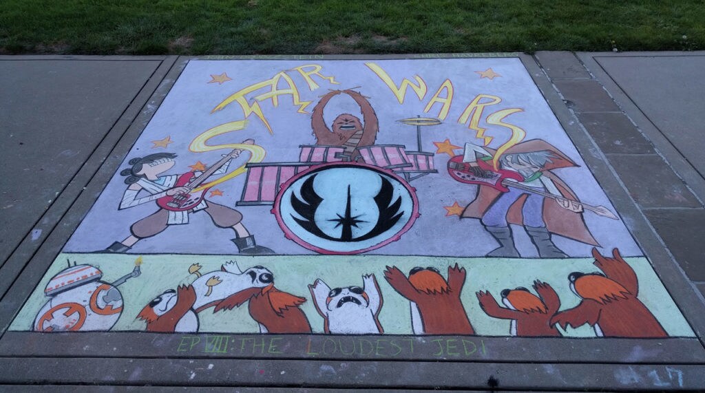 Sidewalk chalk art of BB-8 and a group of rowdy porgs in the audience of a rock show performed by a band consisting of Rey, Luke Skywalker, and Chewbacca on drums.