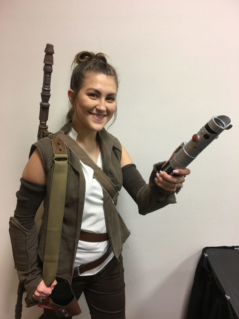 Cosplayer Salina Lopez, dressed as Rey, shows off her lightsaber.