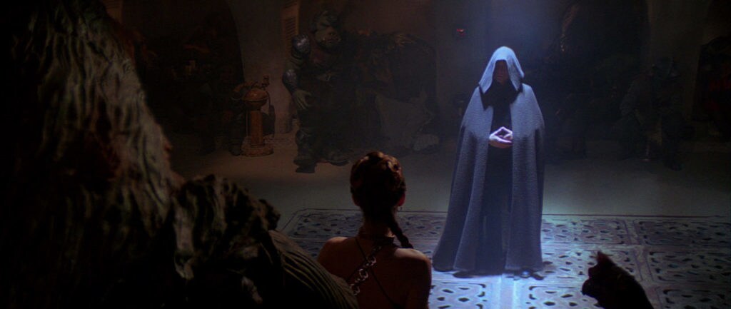 A shrouded Luke stands before Jabba who holds Leia in chains in Return of the Jedi.