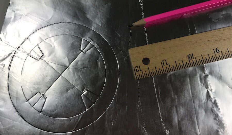 Aluminum foil, a pencil, and a ruler have been used to trace the details that will go on the side of the BB-9E jack-o-lantern.