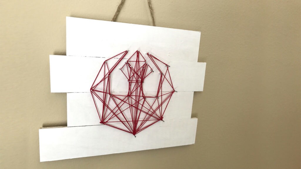 A red string art craft in the shape of the Rebel insignia.