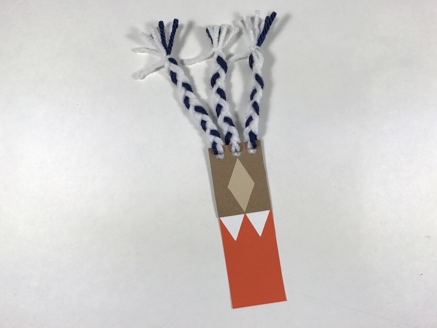 An Ahsoka Tano-inspired cardboard bookmark, with yarn tassels.