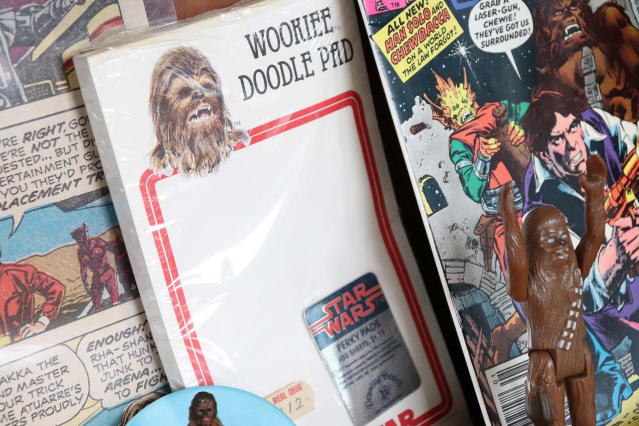 A Wookiee Doodle Pad bearing the image of Chewbacca sits beside a Chewbacca action figure and Star Wars comics.