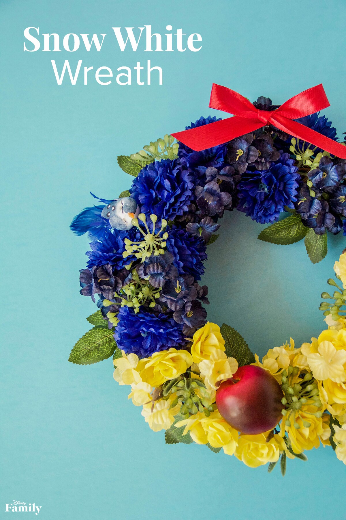 A Snow White themed wreath with blue and yellow flowers, a red bow, and a red apple.