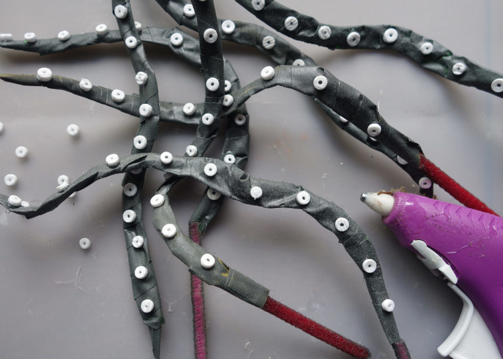 A group of pipe cleaners made to look like tentacles, next to a hot glue gun.