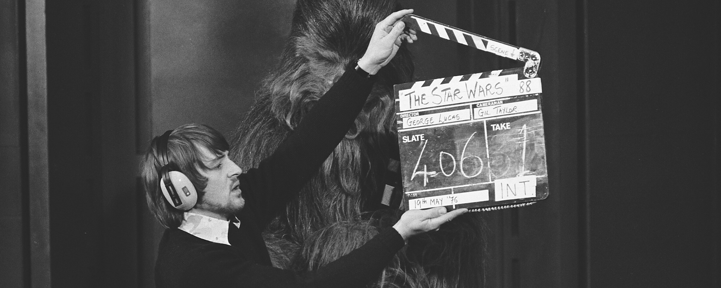 A crew member holds a clapperboard in front of Chewbacca, on the set of A New Hope.