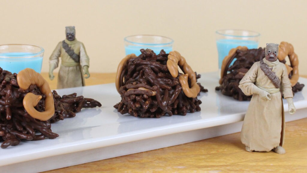 Cookies decorated to look like bantha on a plate next to Tusken Raider action figures.