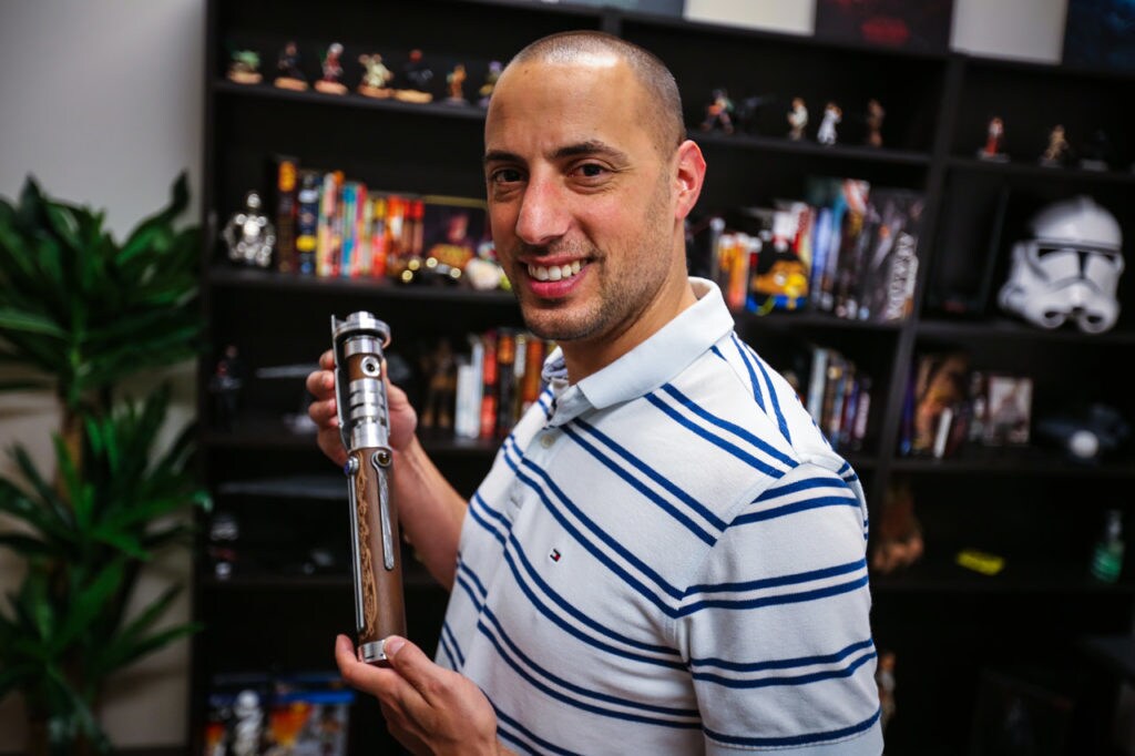 Lucasfilm's Marco Crescenti holding a lightsaber gifted to the Star Wars: The Old Republic games team.