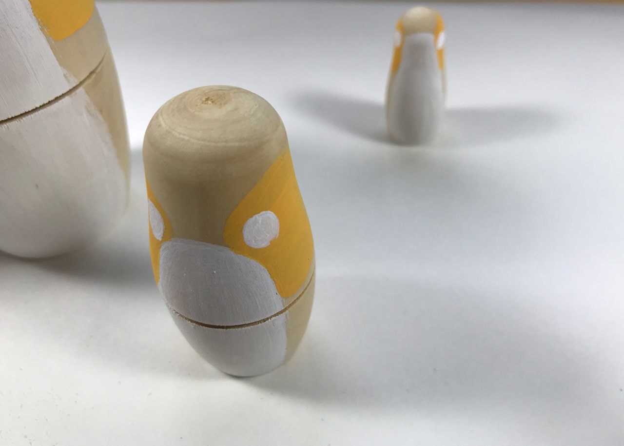 A group of wooden nesting dolls painted to look like Porgs.