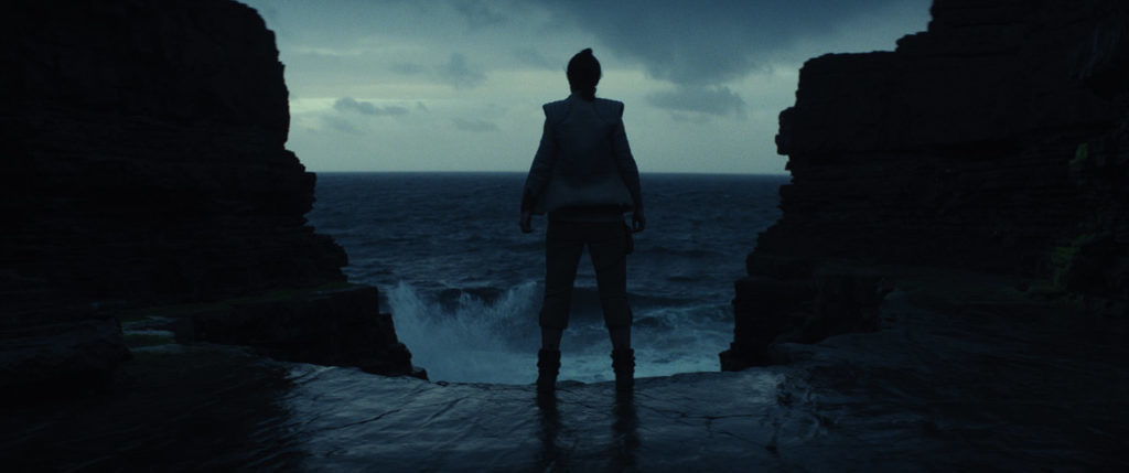 Rey looks out at the ocean in a scene from The Last Jedi.