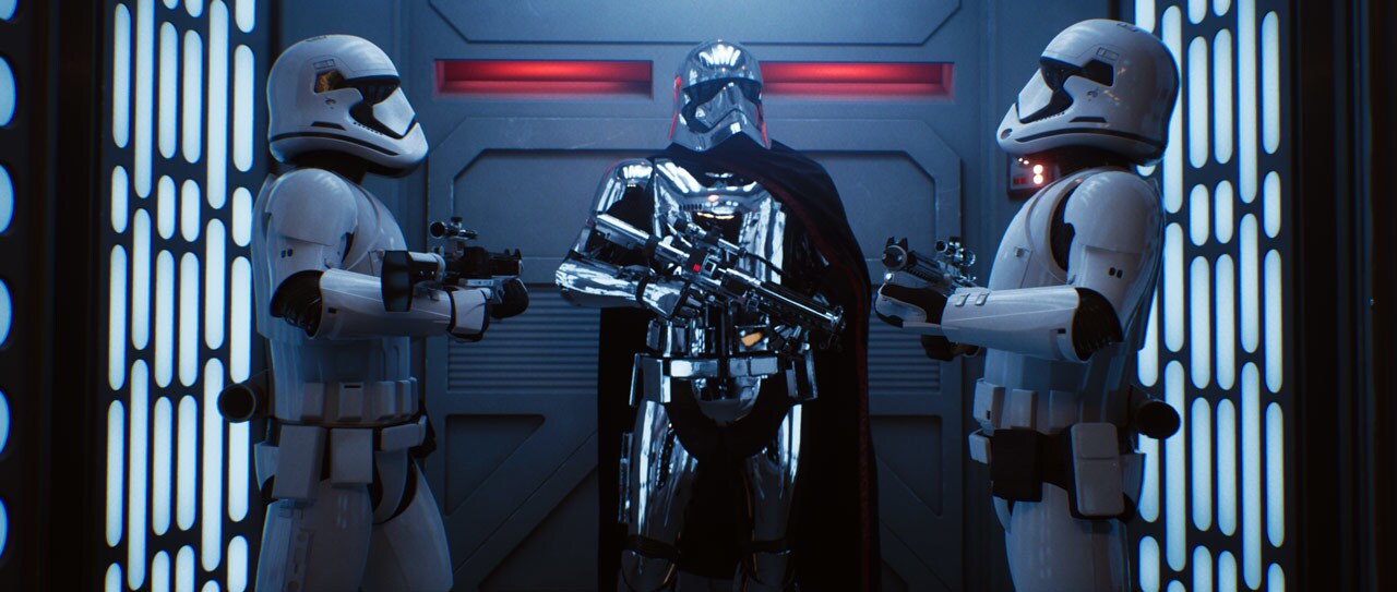 Captain Phasma wields her blaster rifle while flanked by two stormtroopers.