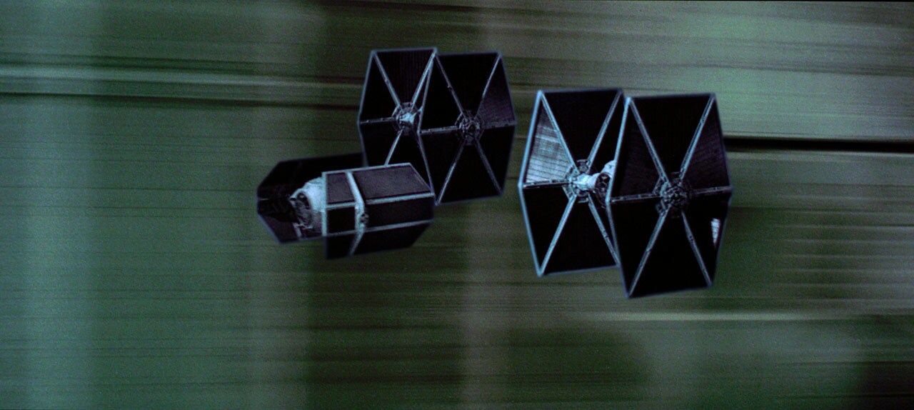 Darth Vader's TIE Advanced x1 flies between two TIE fighters during the Battle of Yavin in A New Hope.