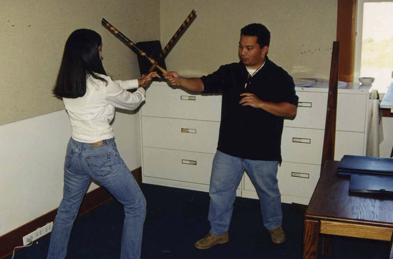 Robles instructs production coordinator Fay David (left) in the use of Escrima sticks.