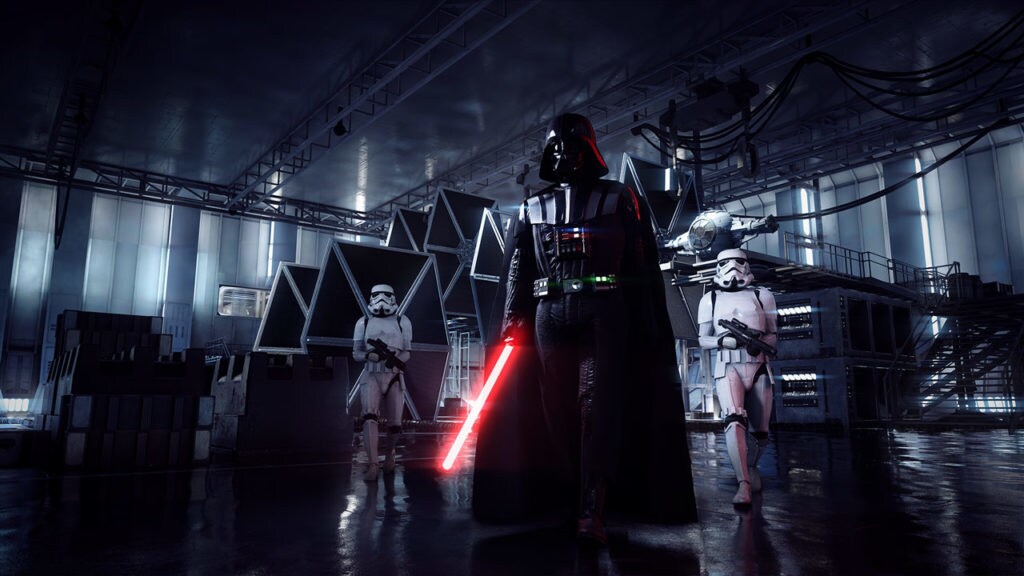 Darth Vader wields a lightsaber as he crosses a TIE fighter hangar while two stormtroopers follow behind him in the game Star Wars Battlefront II.