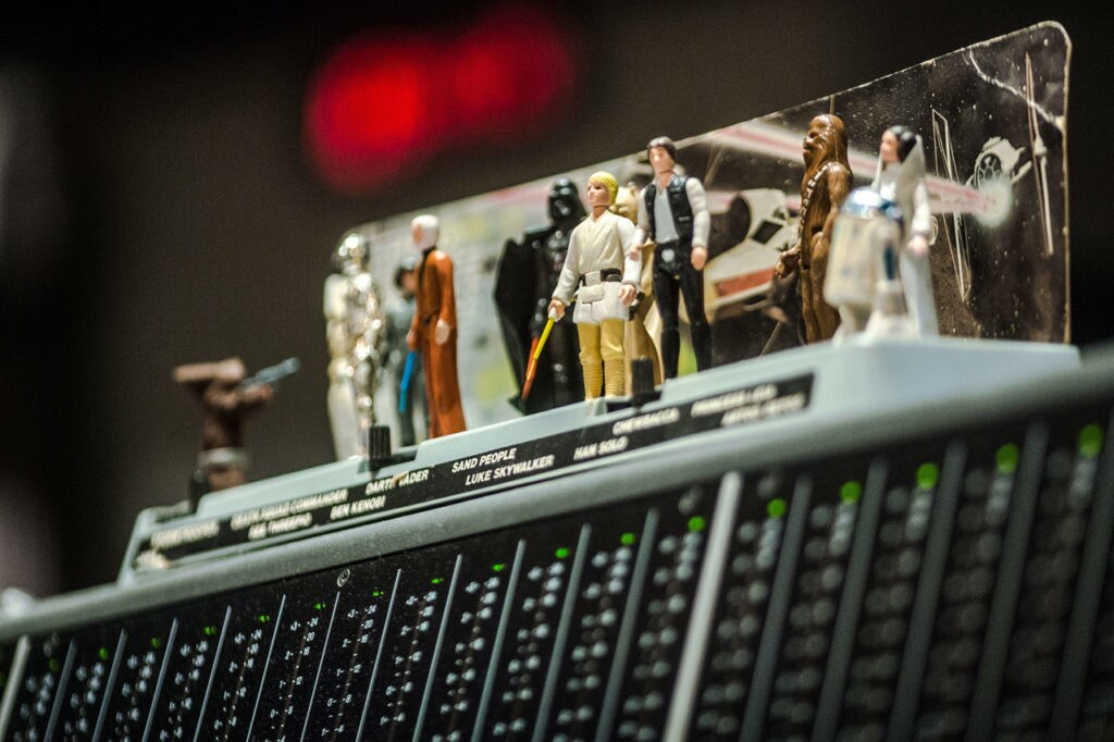 Tiny Star Wars figurines posed on top of a recording console's meter bridge.