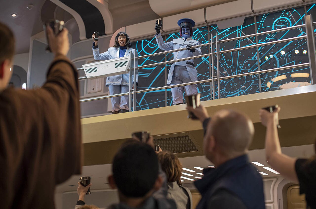 Cruise Director Lenka Mok (left) and Captain Riyola Keevan (right) share a toast with guests in Star Wars: Galactic Starcruiser at Walt Disney World Resort in Lake Buena Vista, Fla. (Kent Phillips, photographer)