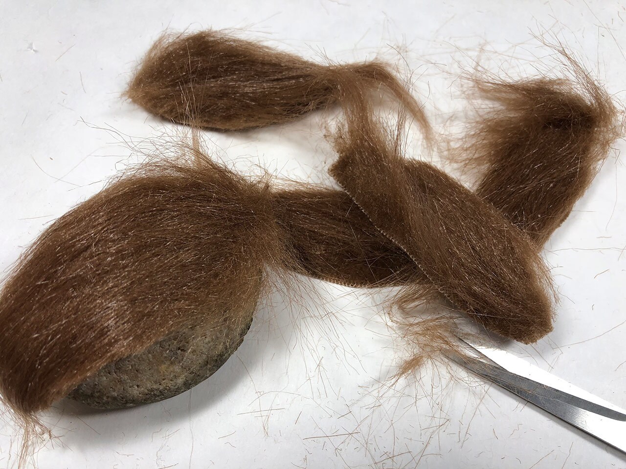 Craft fur is laid over a large stone and trimmed using scissors.