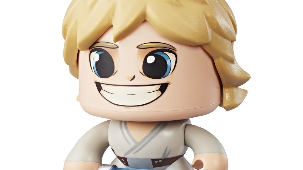 A Luke Skywalker Star Wars Mighty Muggs collectible figure holds a lightsaber with a big smile on its face.