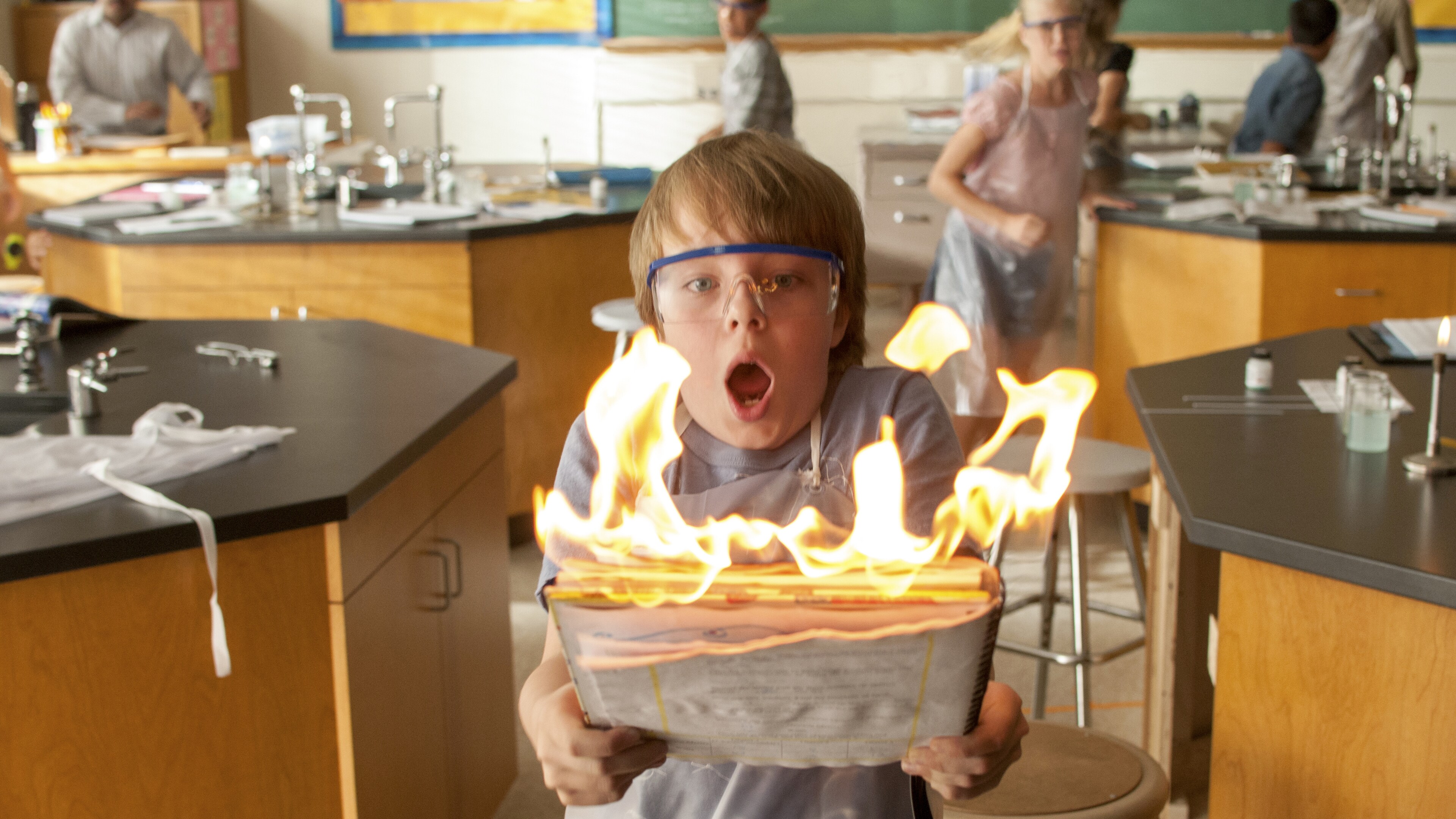 Ed Oxenbould as Alexander Cooper holding flaming paper in a classroom