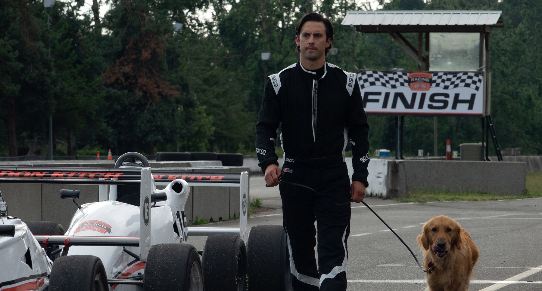 Denny (Milo Ventimiglia) and dog Enzo at the racetrack in the movie "The Art of Racing in the Rain"