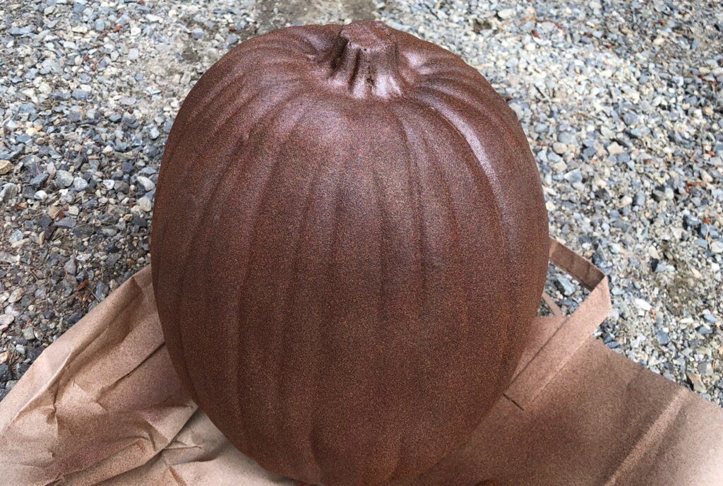 A pumpkin sitting on top of a paper bag.