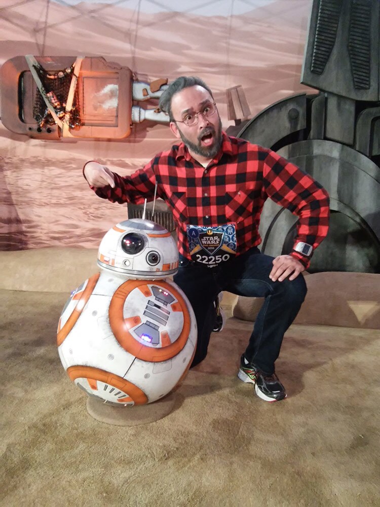 Runner Kirk McDuck, cosplaying as George Lucas, poses with a BB-8 replica.