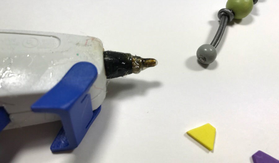 The bottom of a folded gray cord closed shut by a hot glue gun.