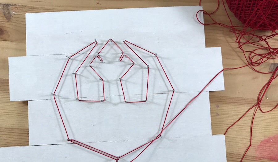 A partially constructed string art craft in the shape of the Rebel insignia.