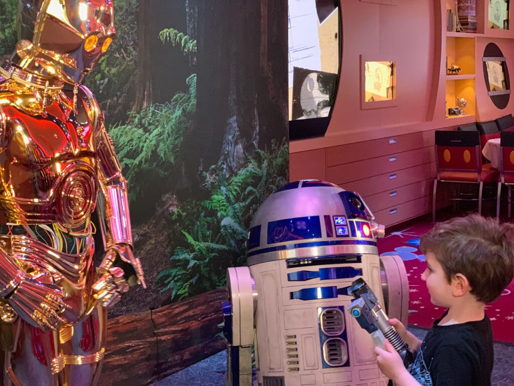 A young fan meets C-3PO and R2-D2 on Star Wars Day at Sea.