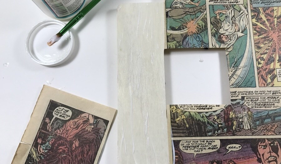 Panels torn from comic books are glued to a wooden picture frame.