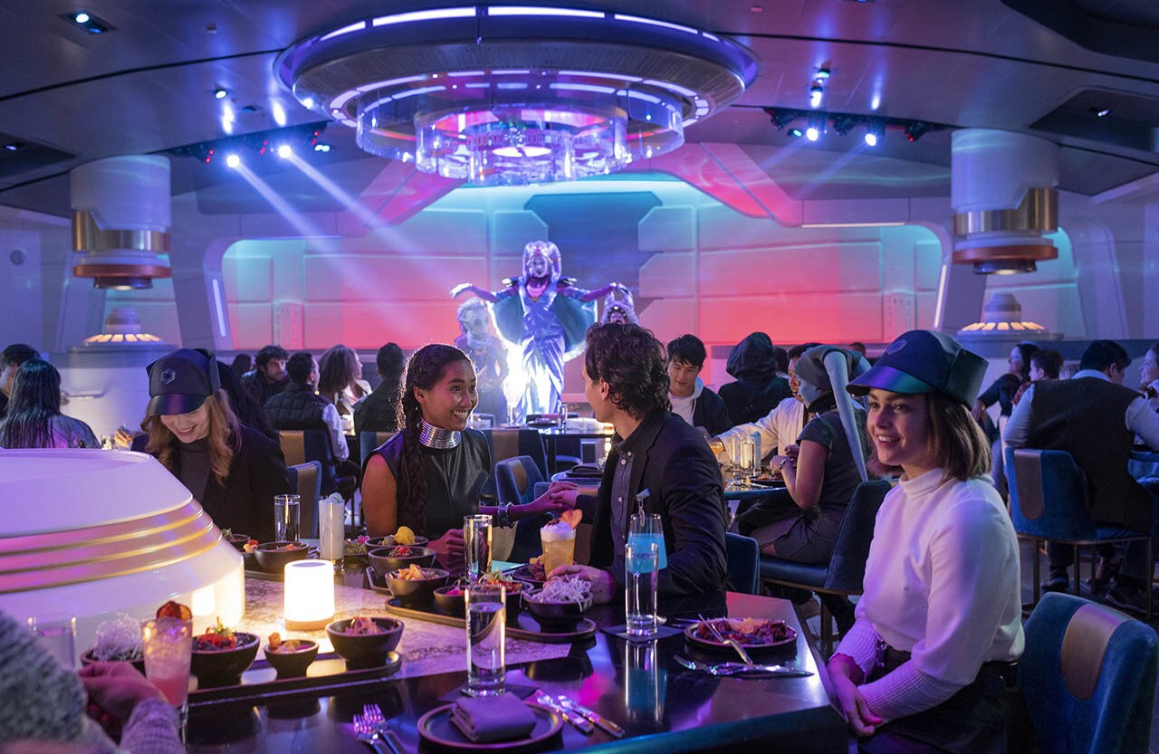 Halcyon starcruiser passengers enjoy a meal and performance by Gaya in the Crown of Corellia Dining Room in Star Wars: Galactic Starcruiser at Walt Disney World Resort in Lake Buena Vista, Fla. (Kent Phillips photographer)