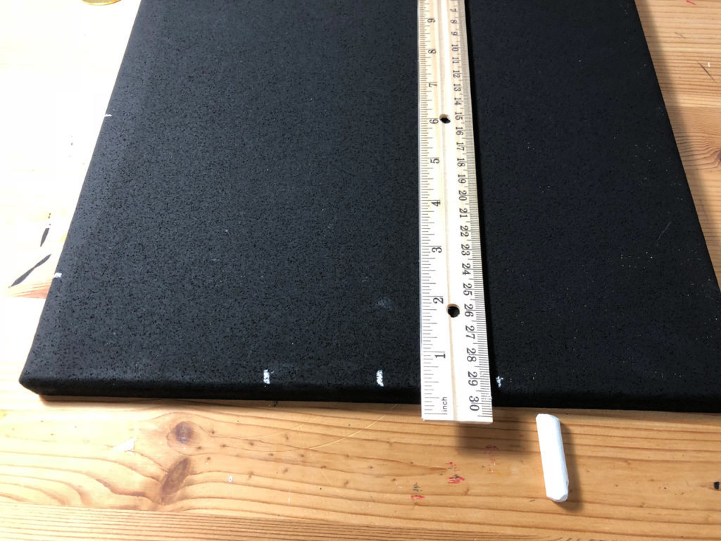 A ruler, placed on a corkboard painted black.
