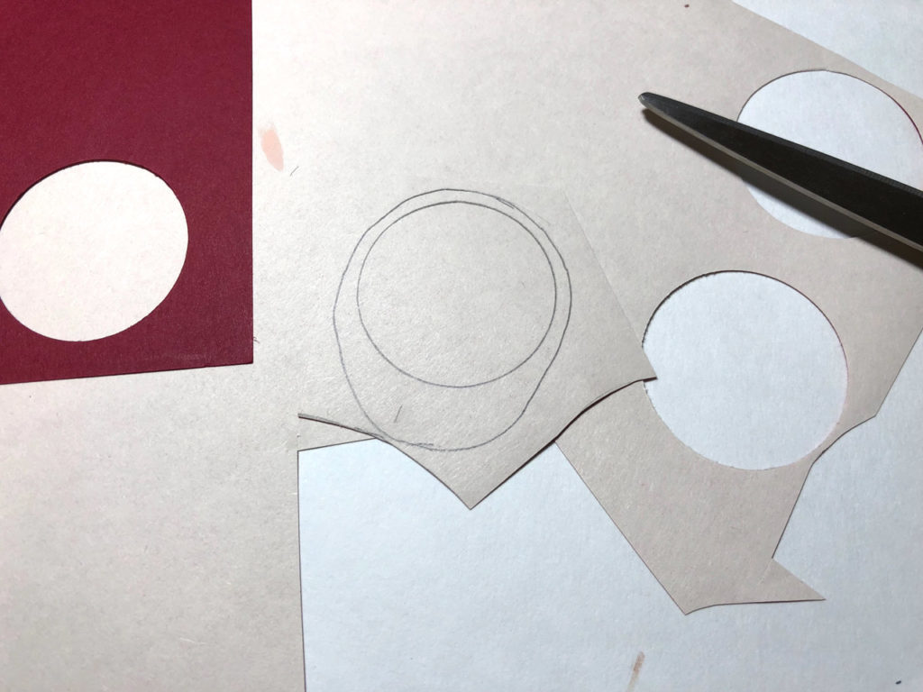 An oval is drawn around a circle on a tan sheet of paper to form the pattern for the handmaiden's hood. This is a bookmark in progress.